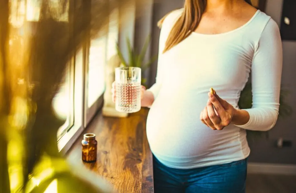 Pregnant woman holding prenatal multivitamin supplement. Pregnancy Care and Naturopathy. Brisbane Livewell Clinic