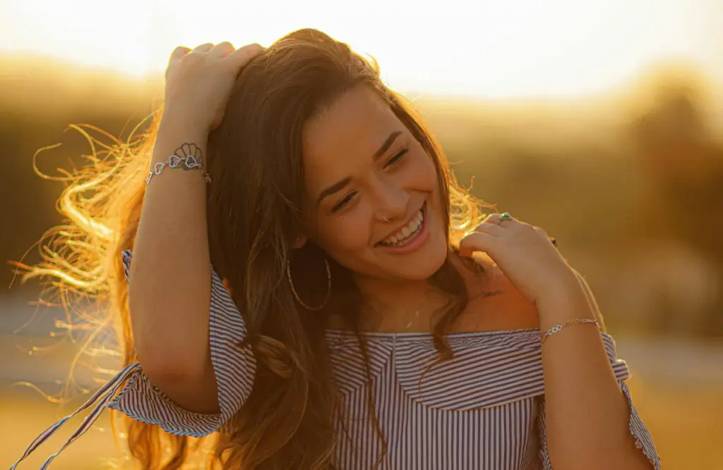Woman smiling joyfully with her hand in her hair. Can Bowen Therapy Help Sciatica. Holistic Counselling for Identity Loss. Brisbane Livewell Clinic