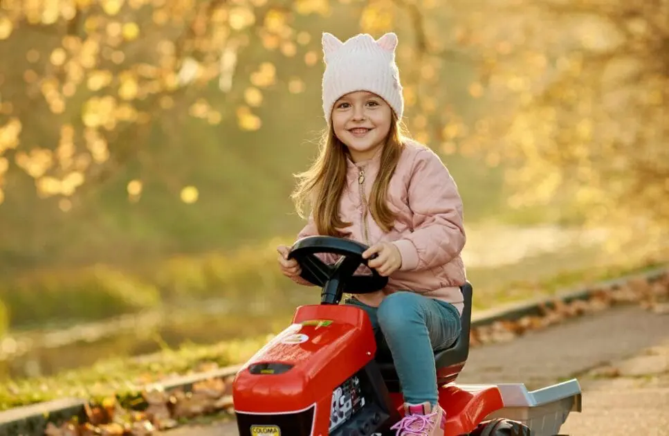 Happy little girl rides a toy tractor around the park. Counselling Hemmant. Heavy Metal Toxicity in Toddlers. Brisbane Livewell Clinic