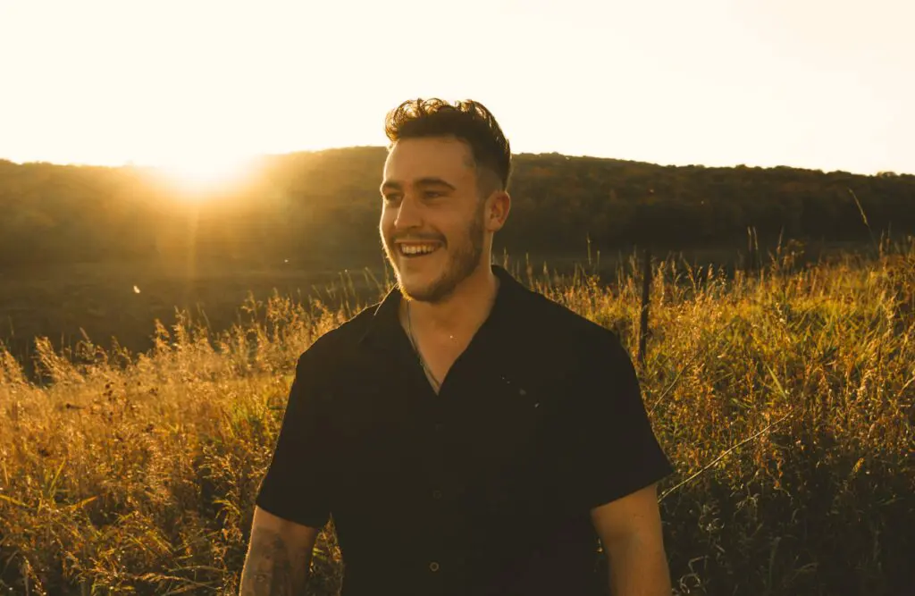 Smiling man in black shirt standing in a field. Naturopathy. Does Bowen Therapy Actually Provide Relief. Brisbane Livewell Clinic