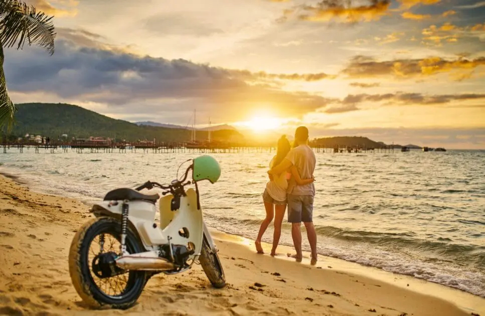 Couple stands on the beach with their motorcycle parked in the sand. Counselling Seven Hills. Brisbane Livewell Clinic