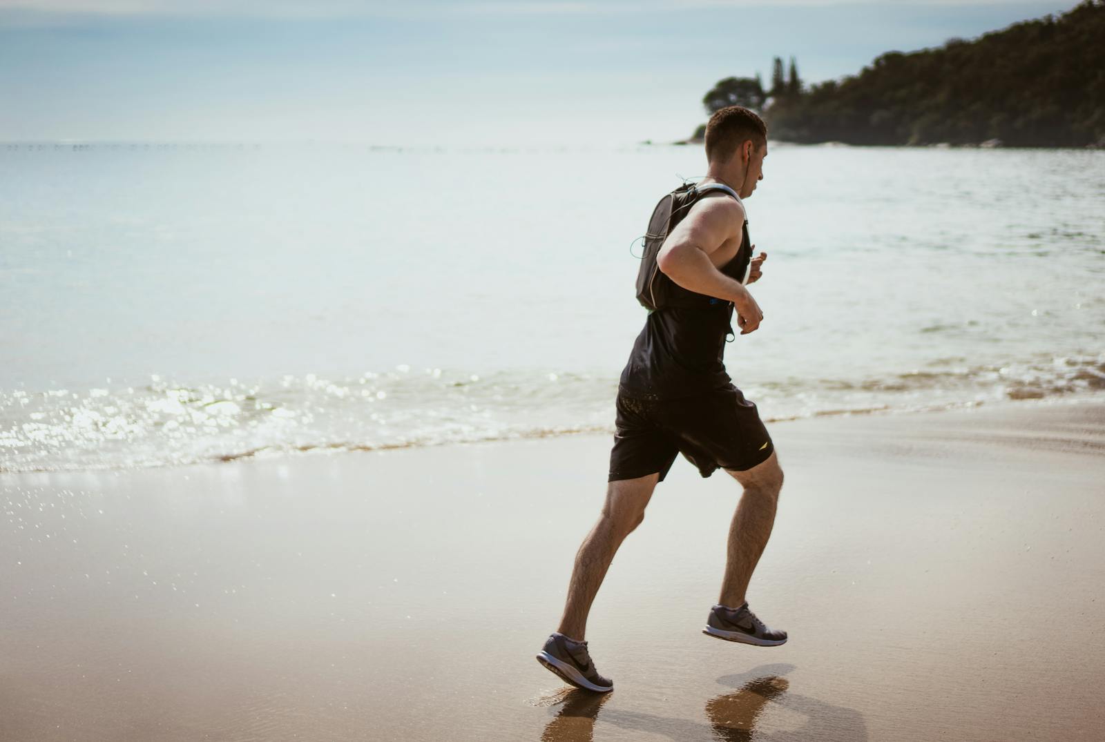 Man Wearing Black Tank Top and Running on Seashore. Causes of Knee Pain