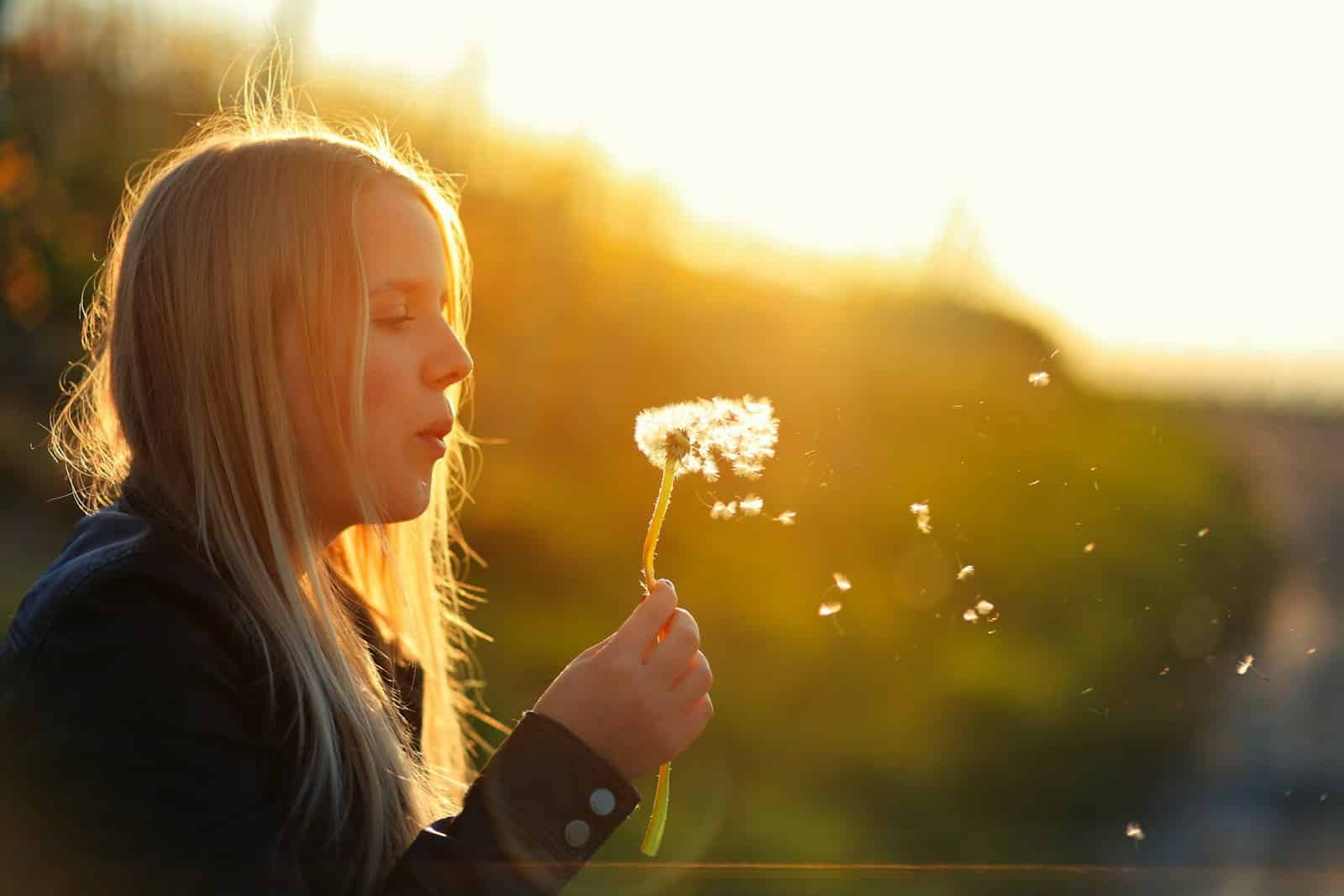 A young girl blowing a dandelion in the sun. Hypnotherapist. Brisbane Livewell Clinic