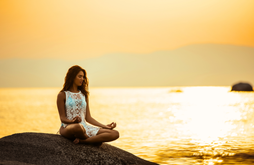 Woman meditating near the ocean. Aftermath of Bowen Therapy. Brisbane Livewell Clinic