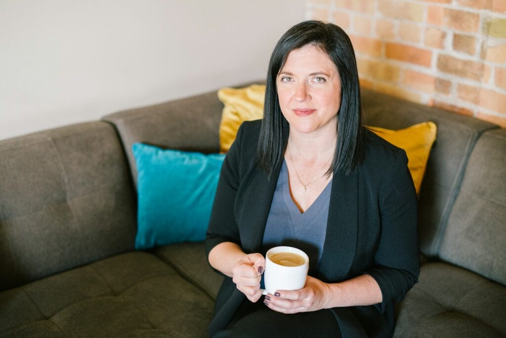 Naturopath holding cup of coffee sitting on sofa. Heavy Metal and Parasite Detox