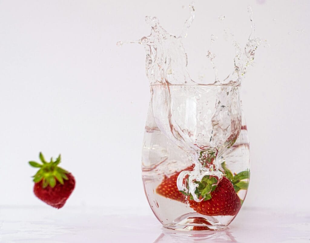A strawberry splashing into a glass of water. Detox from heavy metal and cleanse from parasites