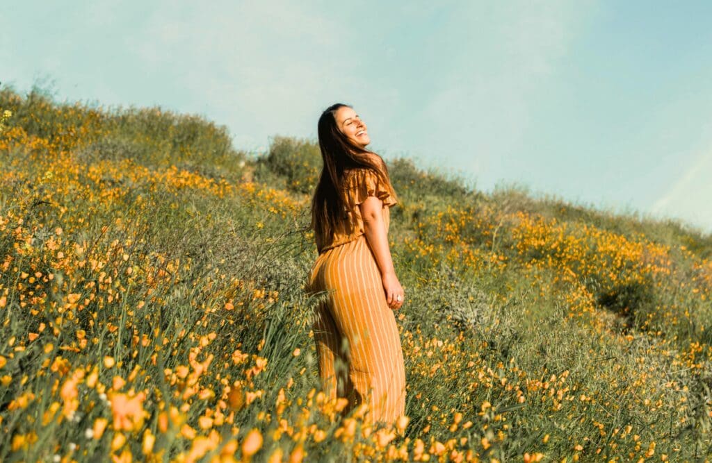 Happy woman standing on a flower field. Clinical Hypnotherapy Bulmba. Depression Hypnotherapy Brisbane. Brisbane Livewell Clinic