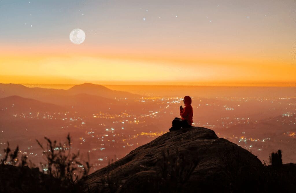 Woman sitting on top of the mountain with a city lights view. Hypnotherapy Melbourne prices. Brisbane Livewell Clinic