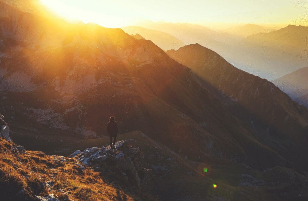 Person standing on rock cliff during golden hour. Hypnosis in Sydney. Brisbane Livewell Clinic