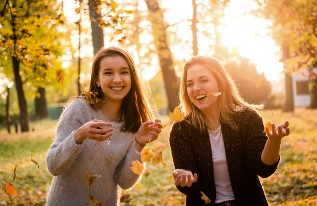 Two female friends having fun in a park filled with fallen leaves. Naturopath Cannon Hill. Brisbane Livewell Clinic, Naturopath Wavell Heights. Pyrrole Disorder
