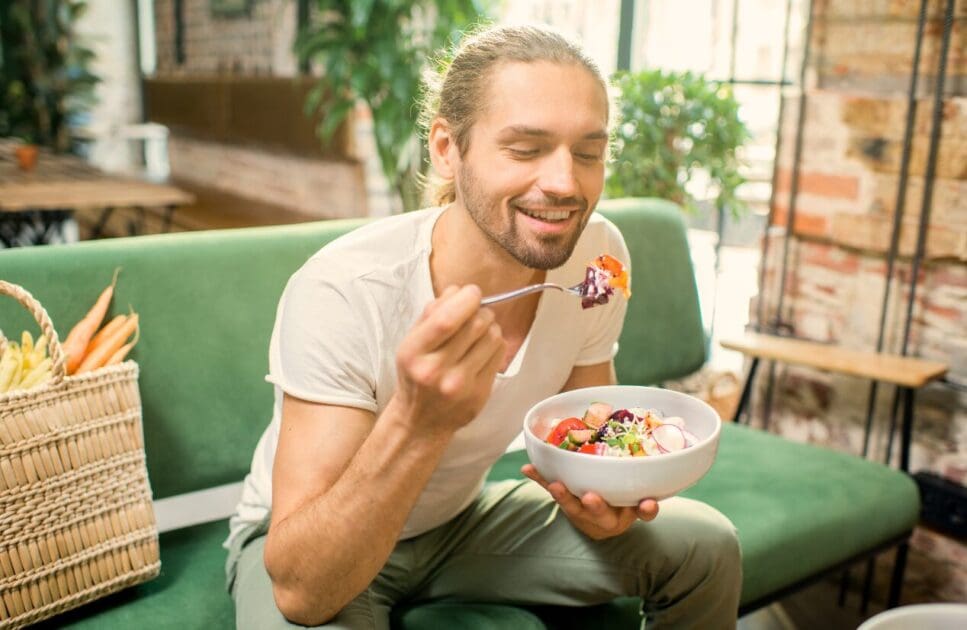 Man sitting on a couch while eating fresh salad. Mood & Food. What is Gut Health Australia? Healthy food and healthy diet. Clinical Nutritionist Cannon Hill. Brisbane Livewell Clinic